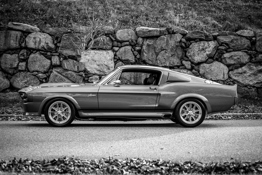 Classic Ford Mustang fastback parked by a stone wall